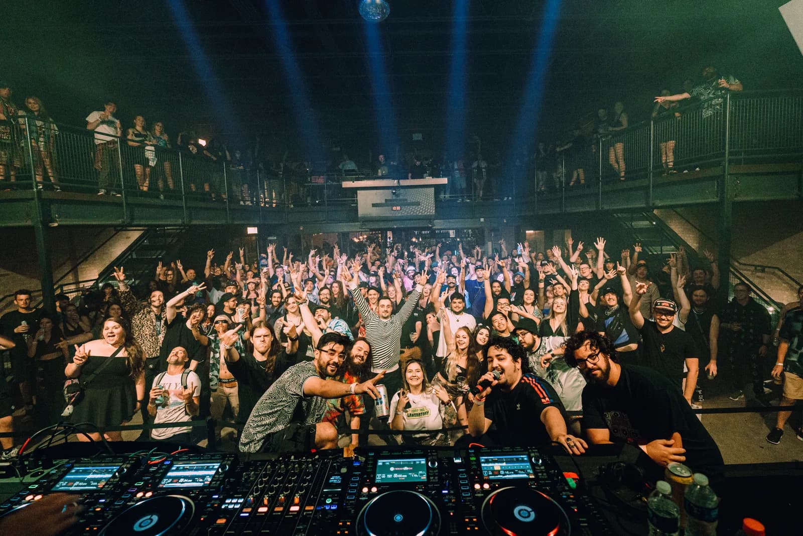 crowd with hands up seen from the dj booth